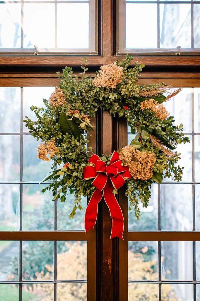A festive wreath hangs on a glass door.