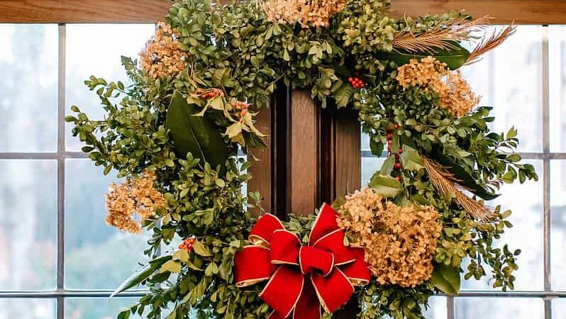 A festive wreath hangs on a glass door.