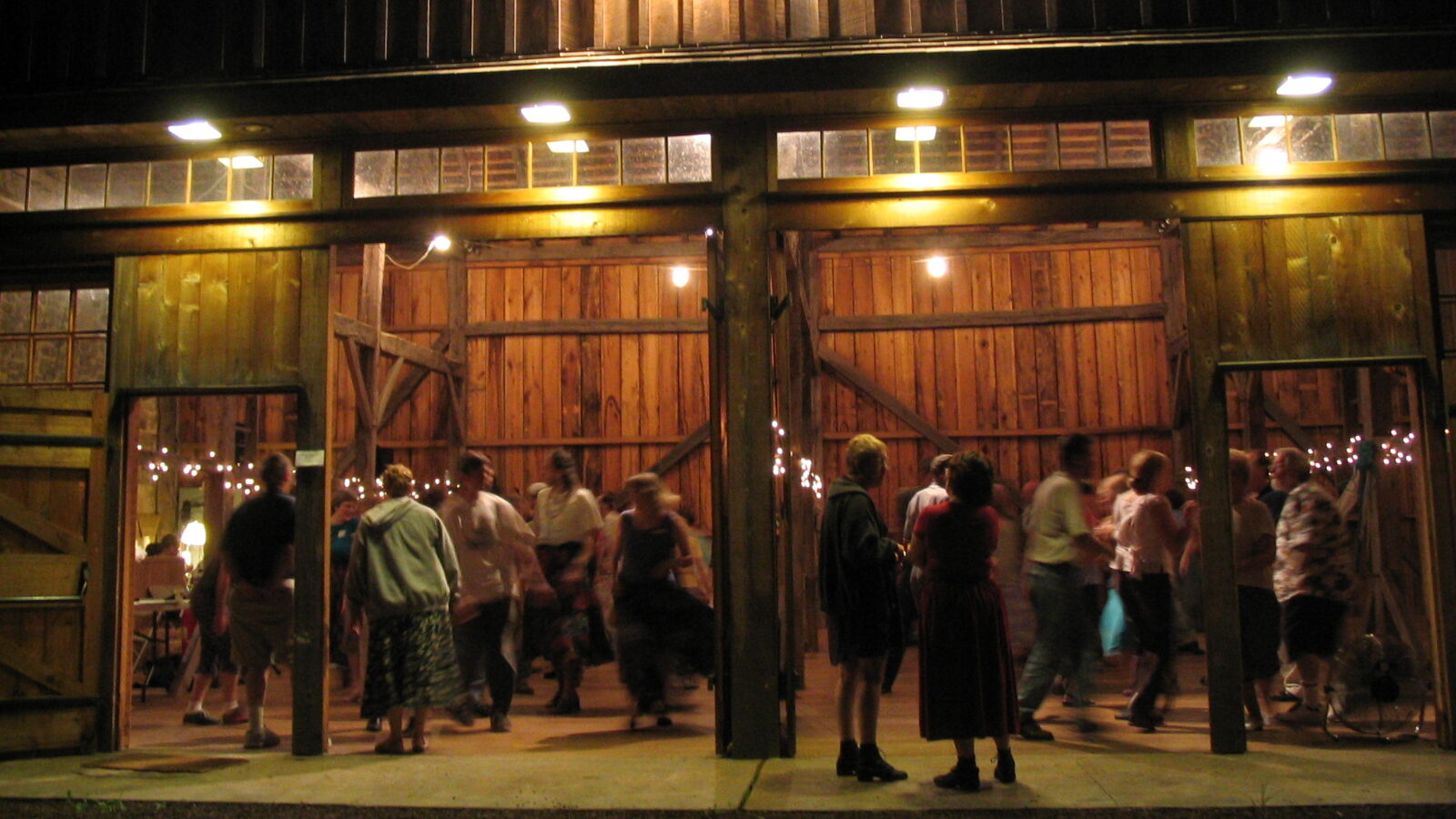 People dancing in a barn at night.