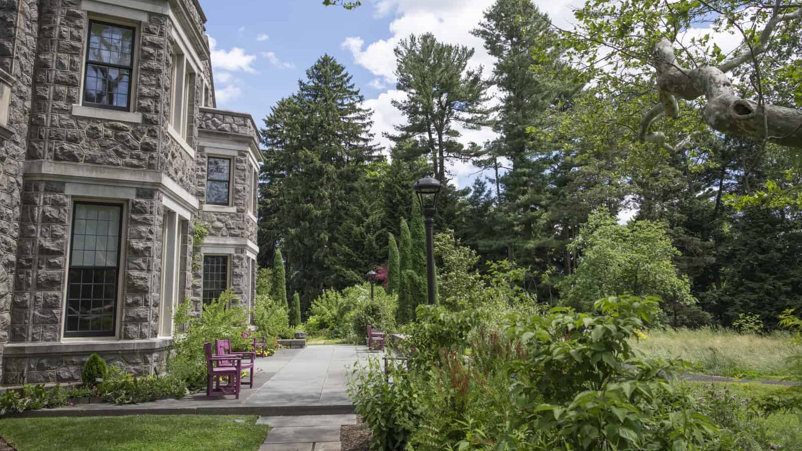 alt text: A stone house on the left overlooks a green garden in early June.