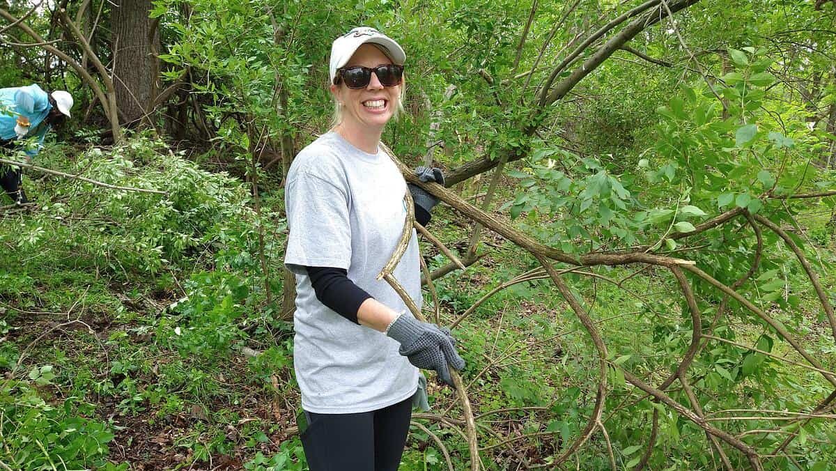 a woman in sunglasses smiling while removing invasives