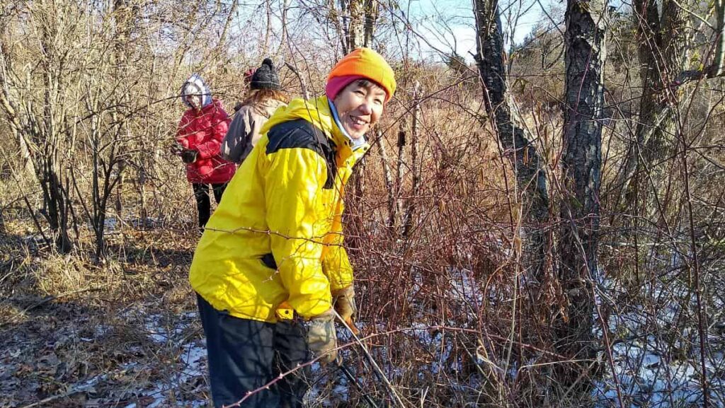 Volunteer smiling while clipping invasive vines