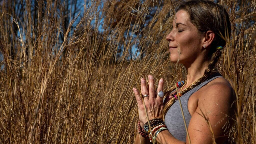 A woman with eyes closed poses with hands together