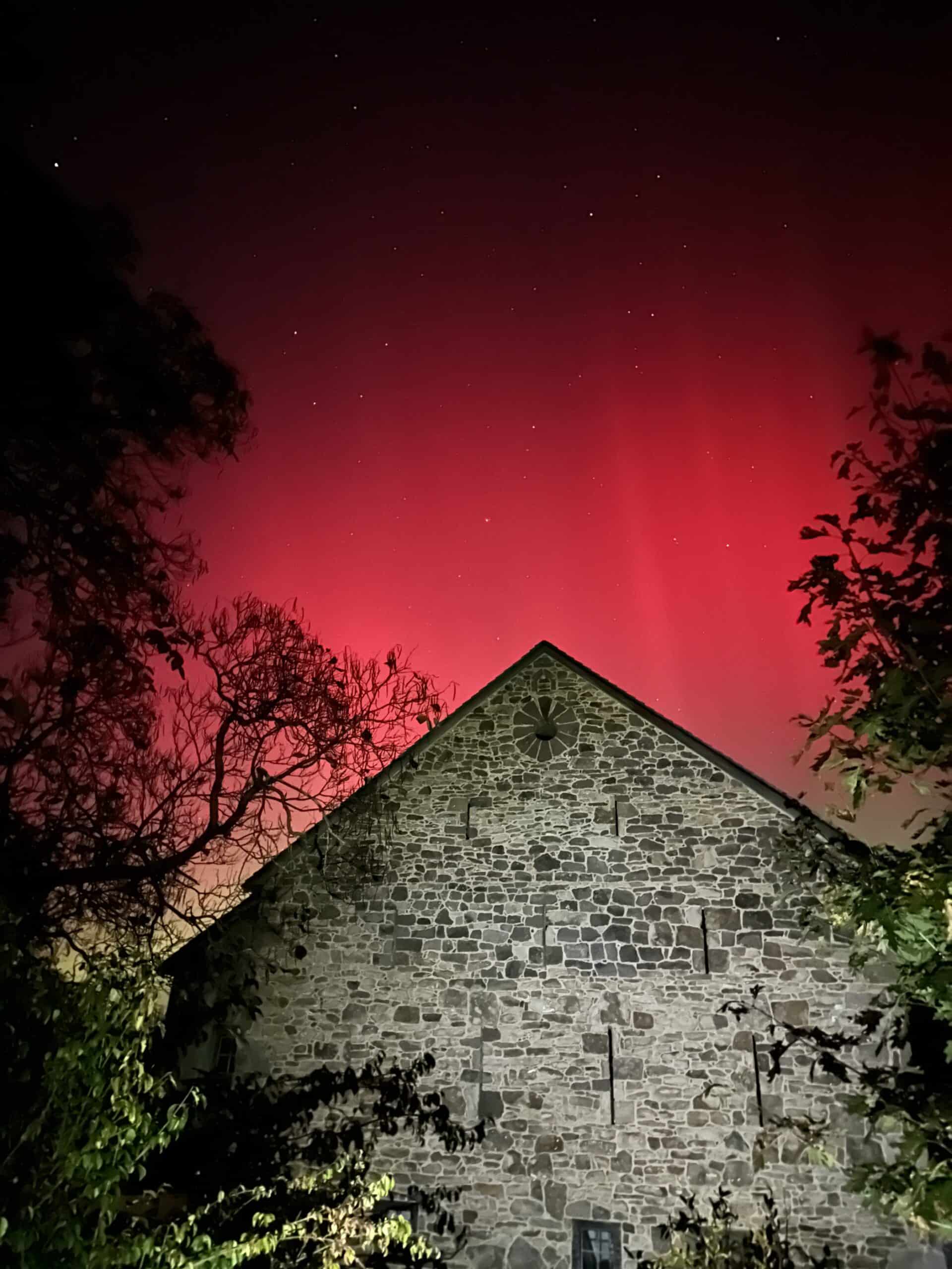 The Aurora borealis above a stone barn.