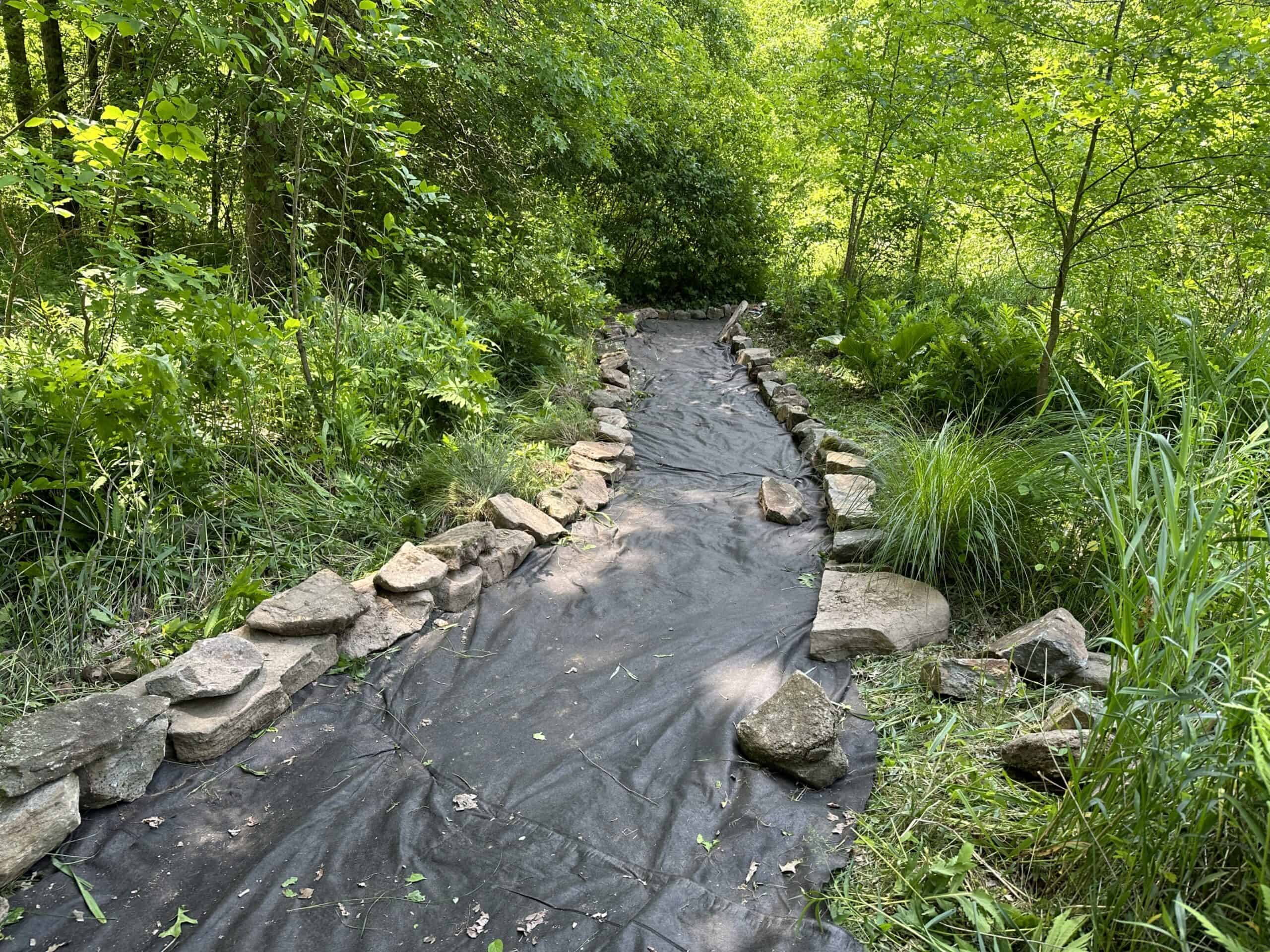 Creek Trail improvement project with rocks lining edges of trail that will be backfilled with gravel