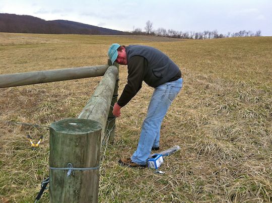 man fixing a wooden fence post