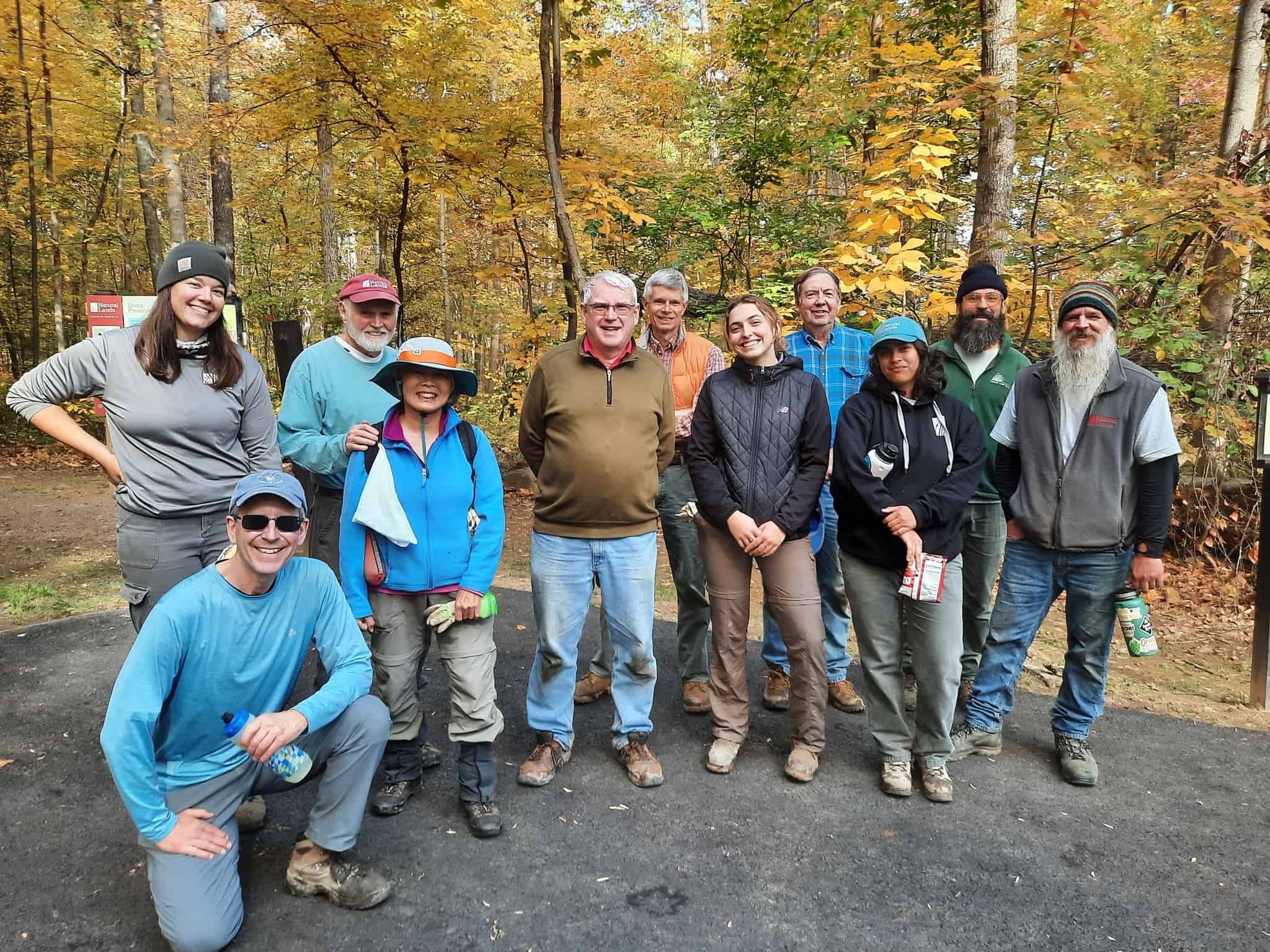 A group of volunteers and Natural Lands staff pose in a forested setting.