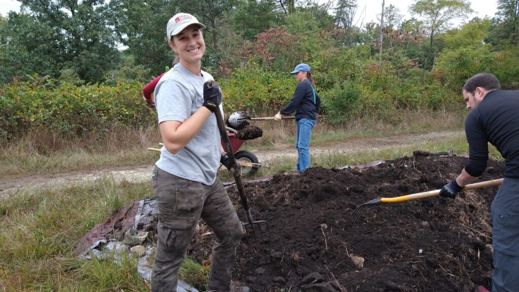 person with a pitchfork moving soil