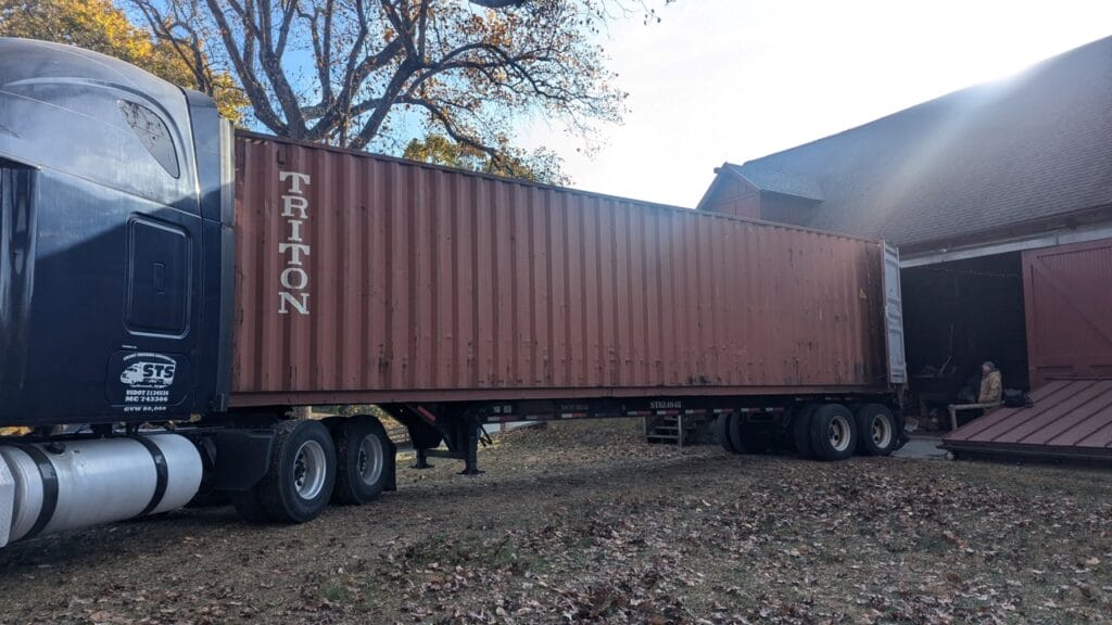 A tractor trailer backed up to the opening of an old stone barn