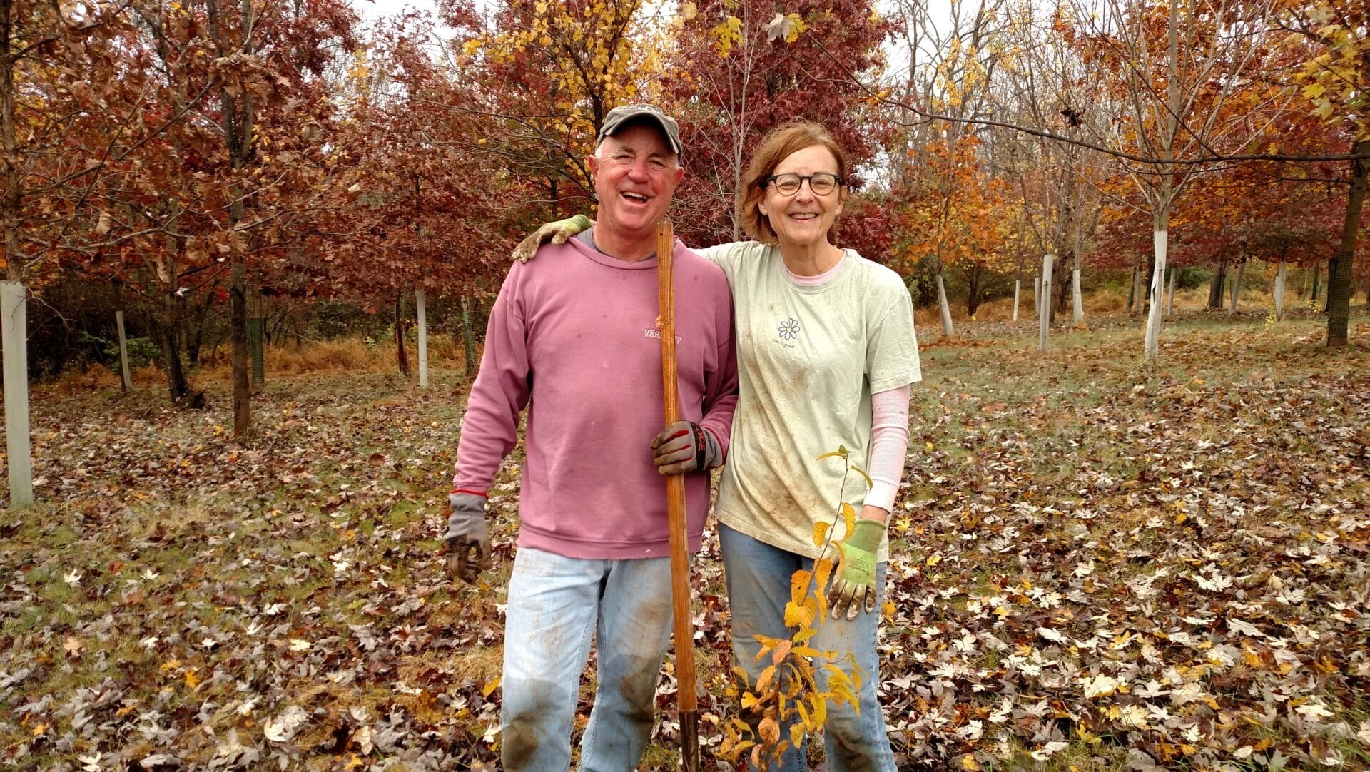 a man and woman smiling while planting a shrub