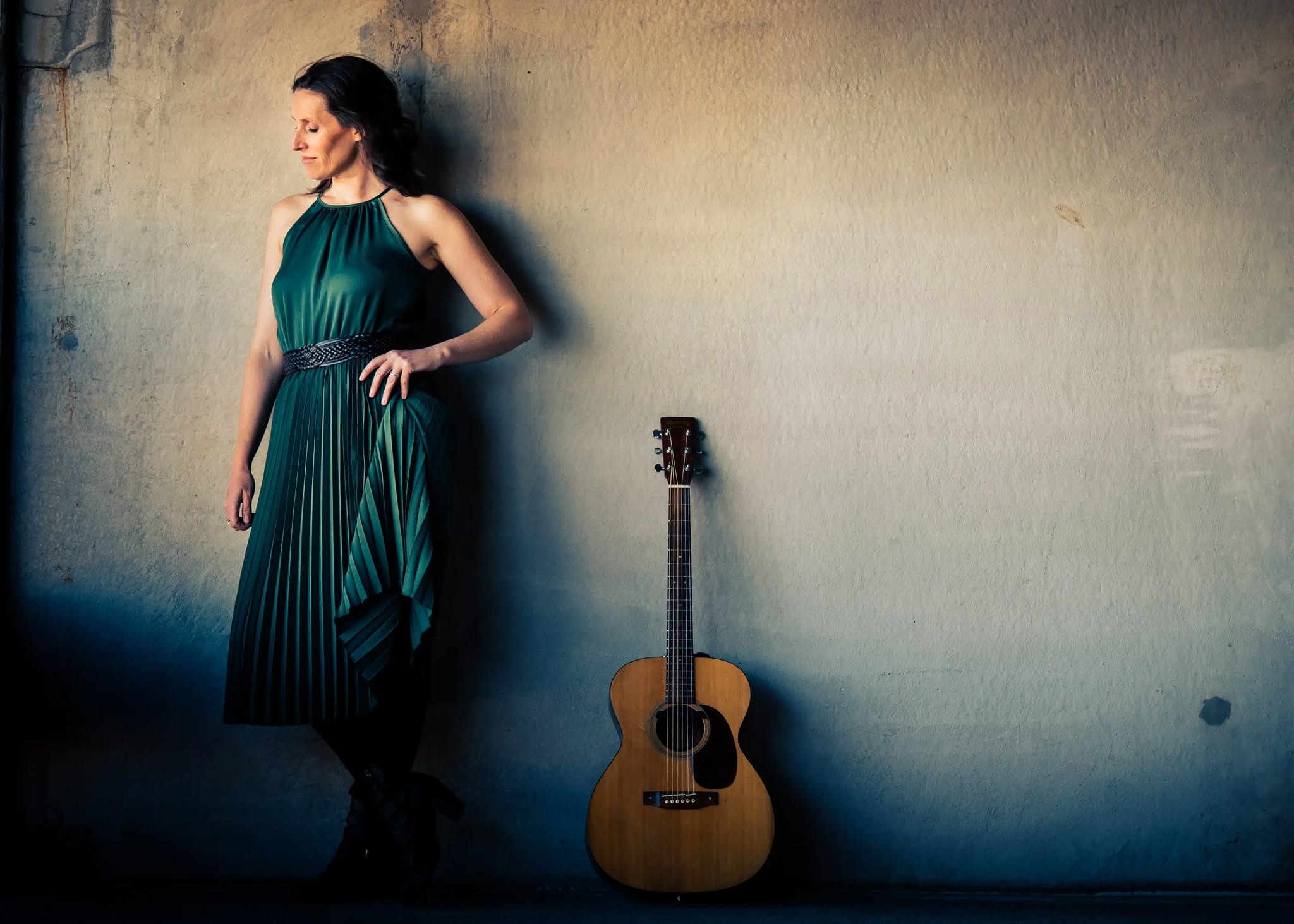 a woman in a long dress beside an acoustic guitar