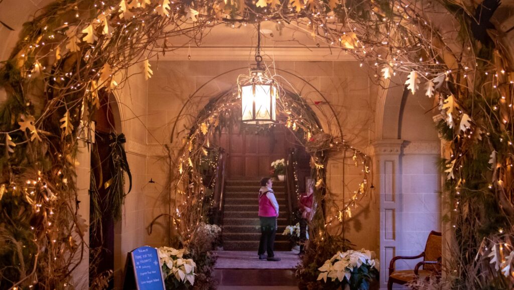 interior with natural holiday decor, a chandelier, and a person standing in the archway