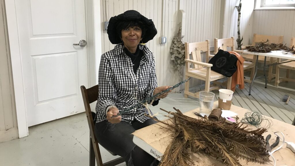 volunteer sitting at a table working on natural holiday decor