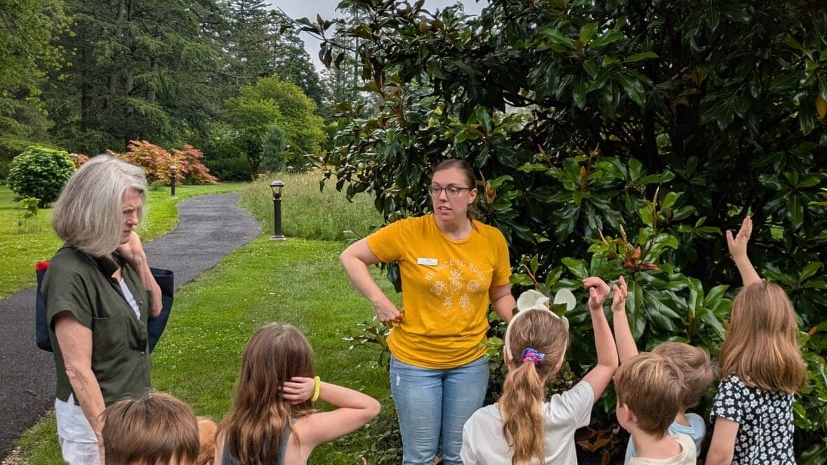 an instructor with a group of kids on a tour in a garden