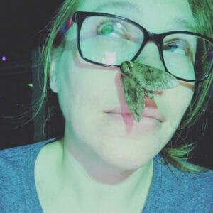 A woman with classes with a moth on her nose