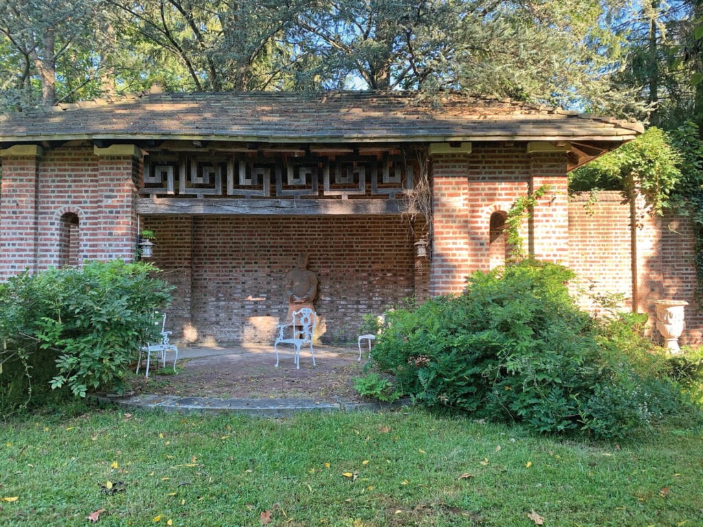 a red brick structure with white chairs on a patio
