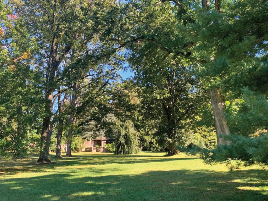 a landscape view of lawn, trees, and a brick building in the background
