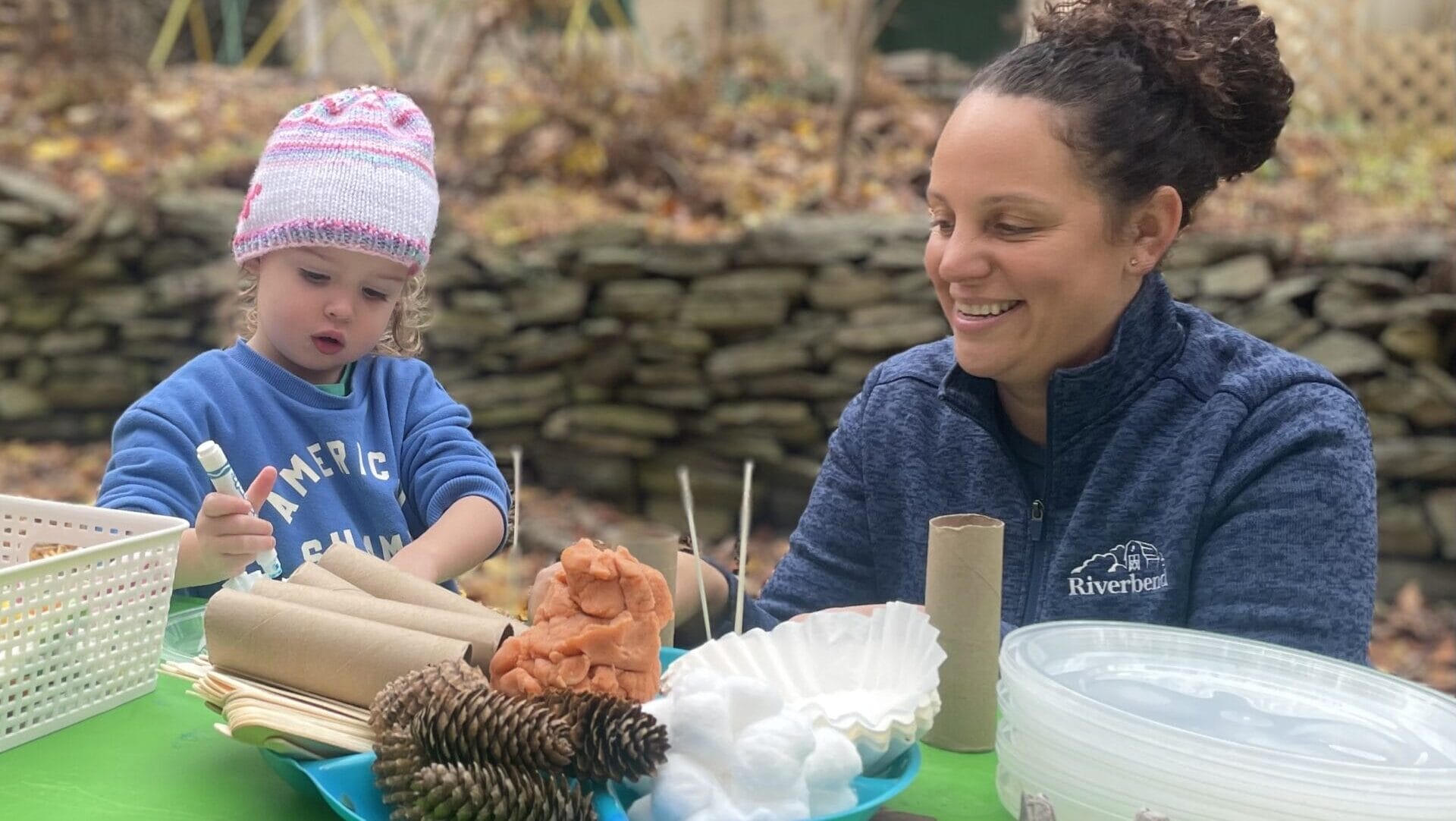 A woman and child making a craft outdoors.