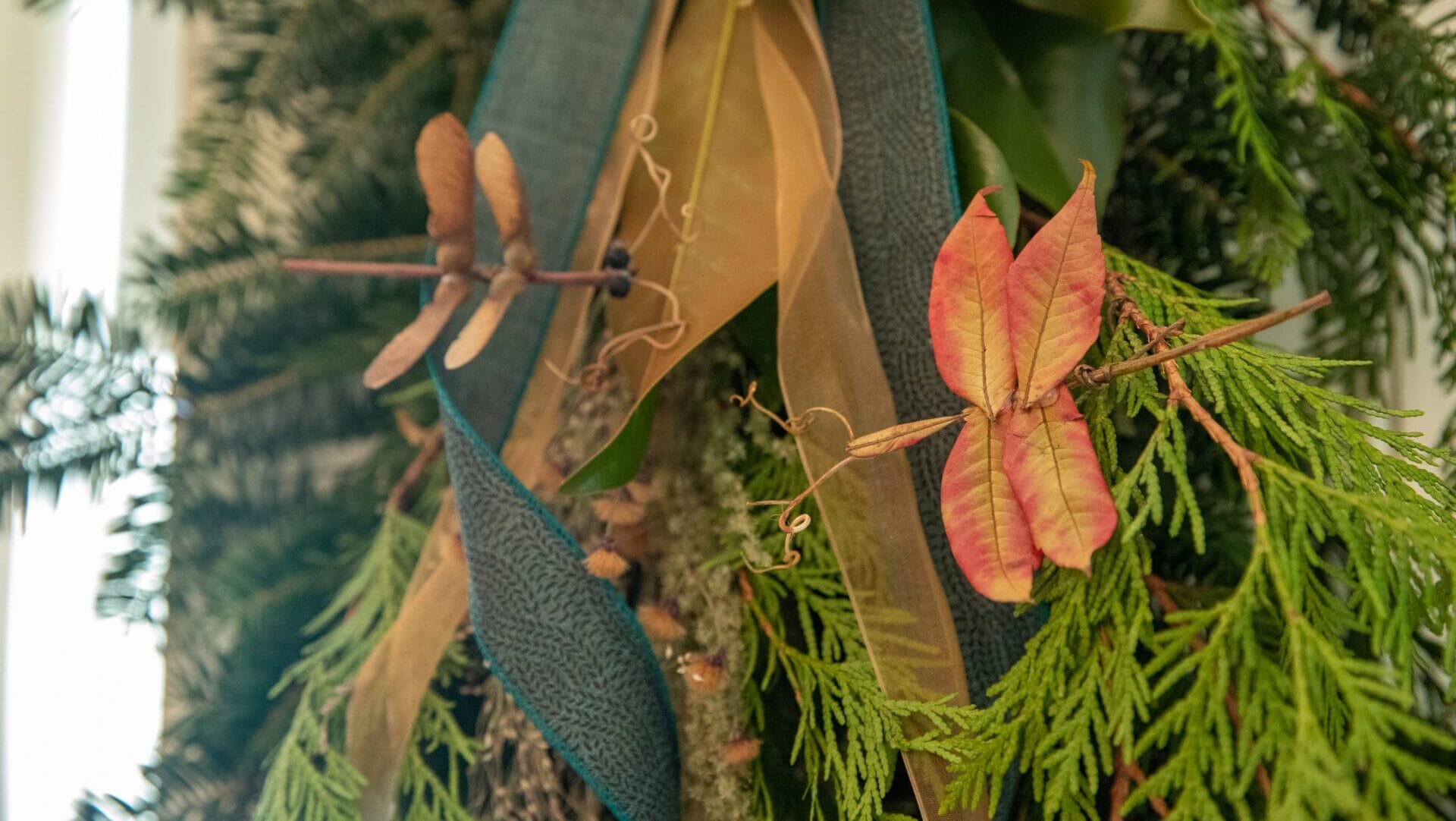 Dragonflies made out of dried plant materials attached to swag.