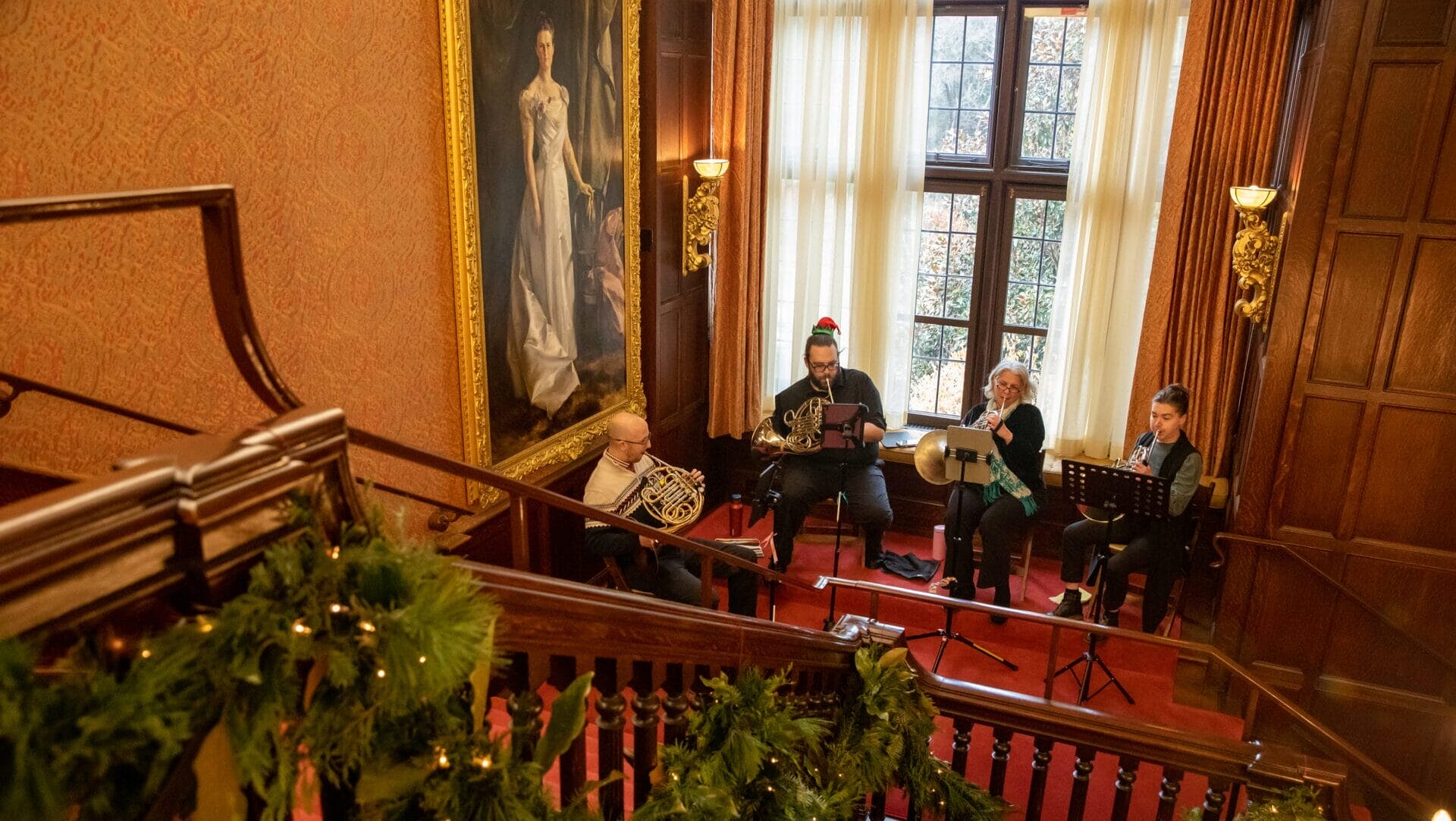 People playing horned instruments on a stairs landing.