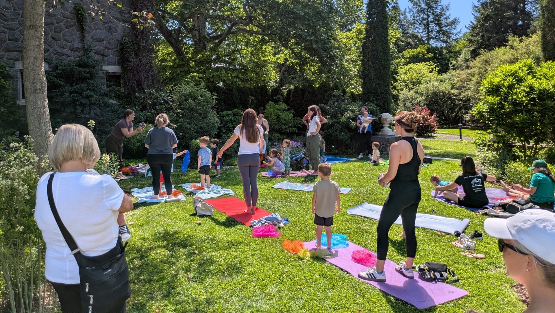 Women and children on yoga mats on a lawn.