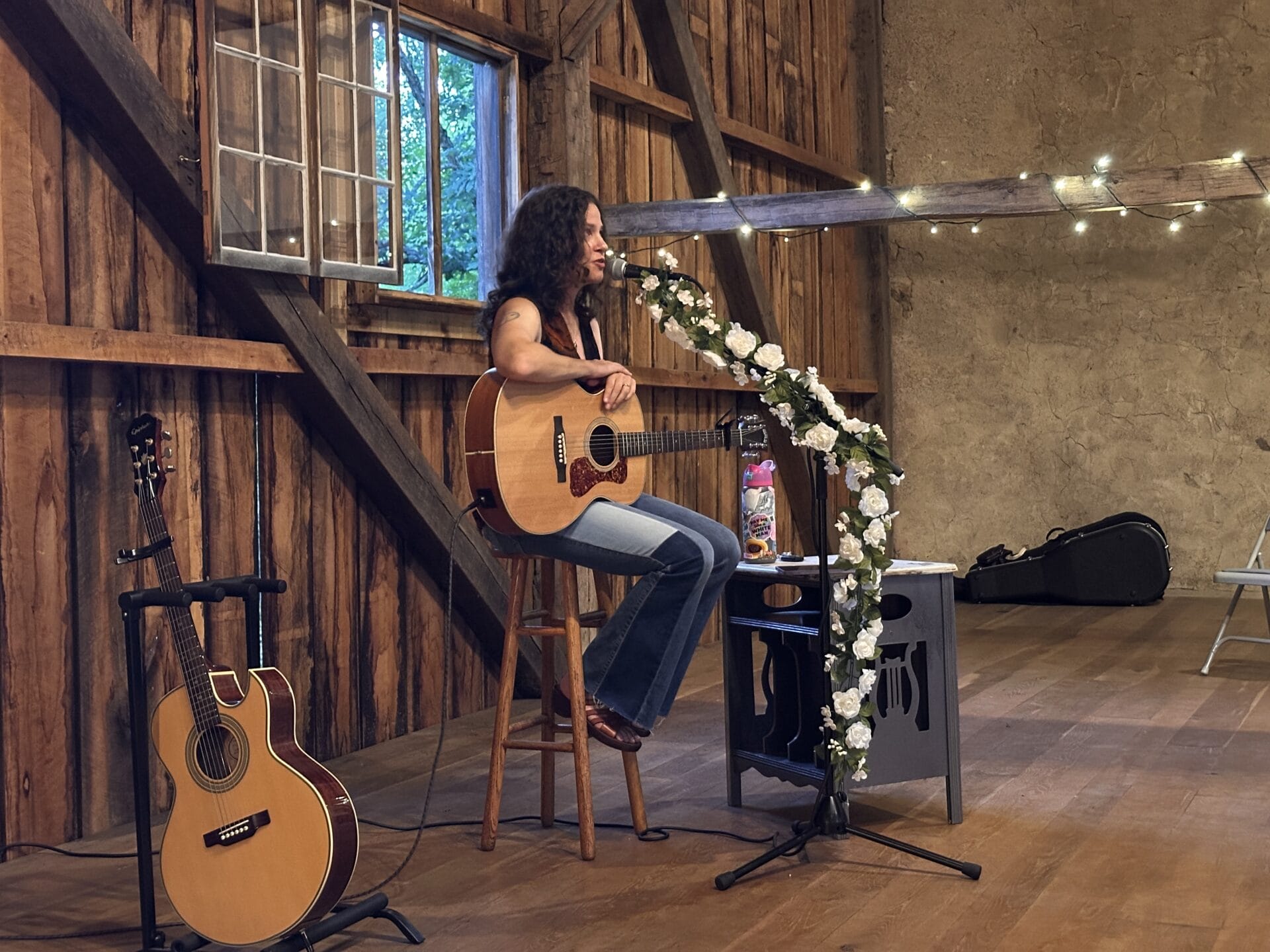 A singer with a guitar playing in a barn.