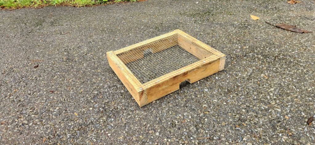 A box of 2x4s with wire mesh overtop on the ground